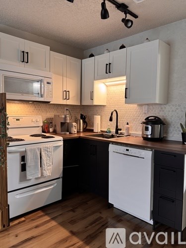 A kitchen with white appliances and wooden floors.
