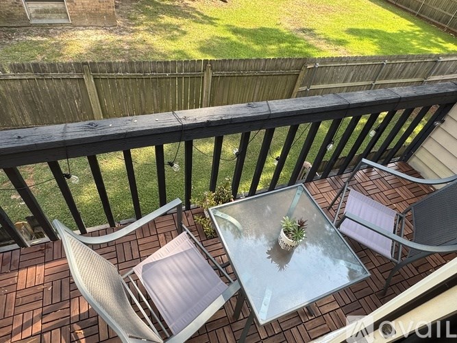 A glass table with a potted plant on it sits on a wooden deck.