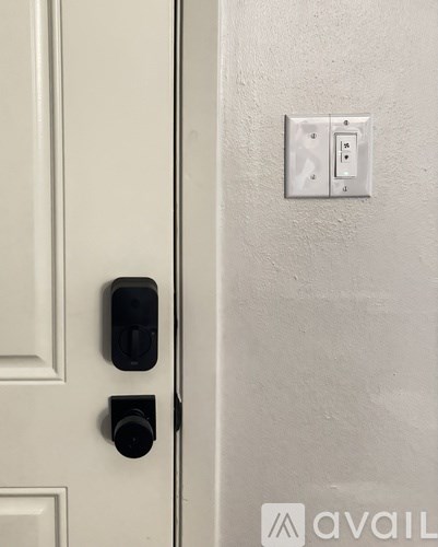 A white door with a black handle and a white light switch on the wall.