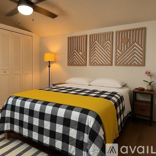 A bedroom with a bed covered in a black and white checkered comforter and a yellow throw blanket.