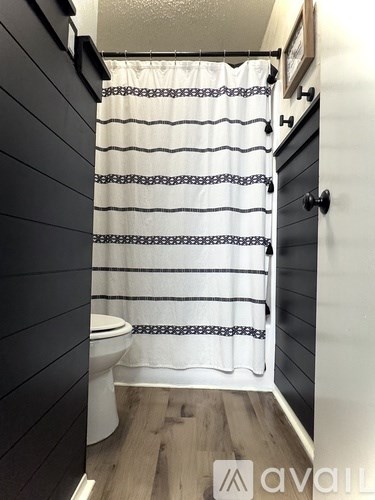 A bathroom with a toilet and a shower curtain.