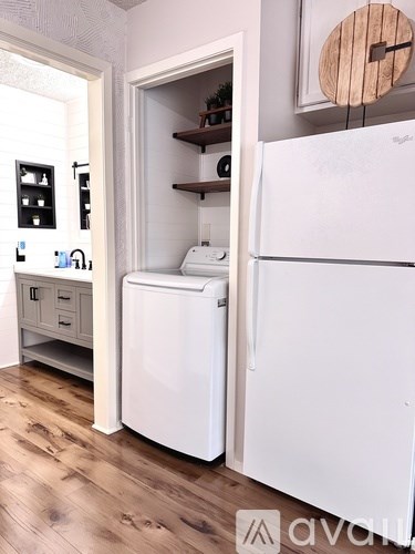 A white fridge and dishwasher in a kitchen with wooden floors.