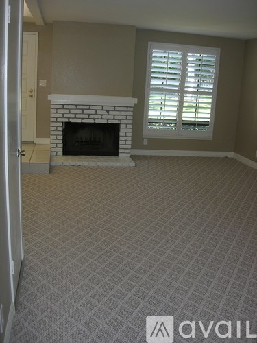 A room with a fireplace and a window with shutters.