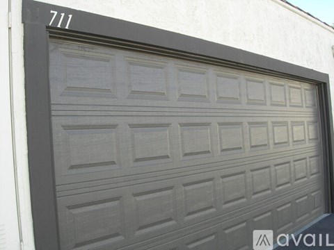 A black garage door with the number 711 on the wall above it.