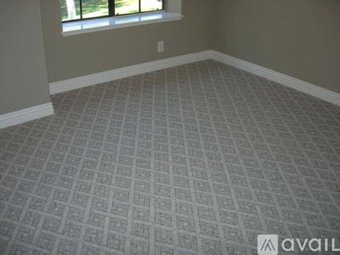 A room with a carpeted floor and a window.
