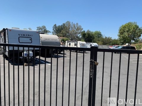 A white RV with the word "Viking" on it is parked behind a black fence.