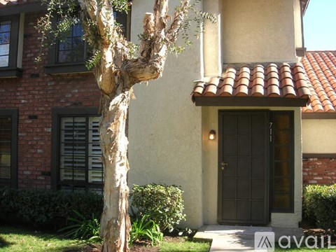 A tree in front of a house with a sign that says "available".