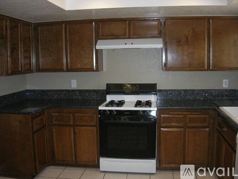 A kitchen with a white stove top oven and wooden cabinets.