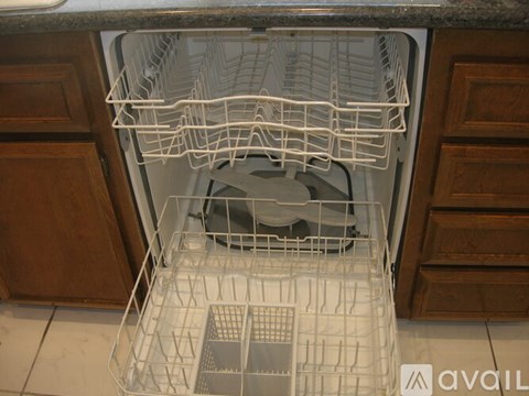 A white dishwasher with the door open and a white dish rack inside.