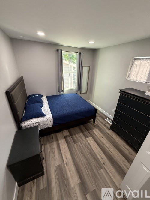 A bedroom with a bed, dresser, and window.