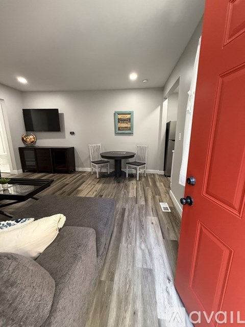 A living room with a grey couch and a red door.