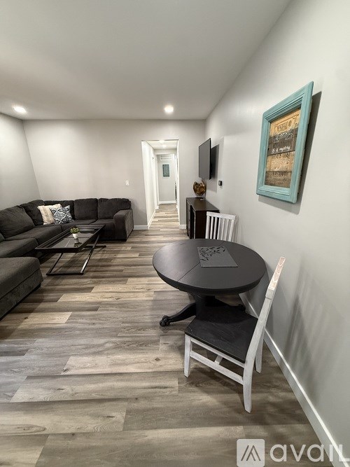 A living room with a black couch and a wooden floor.