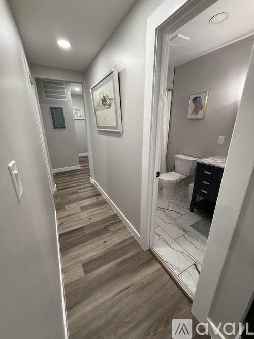 A hallway with wood flooring and white walls.