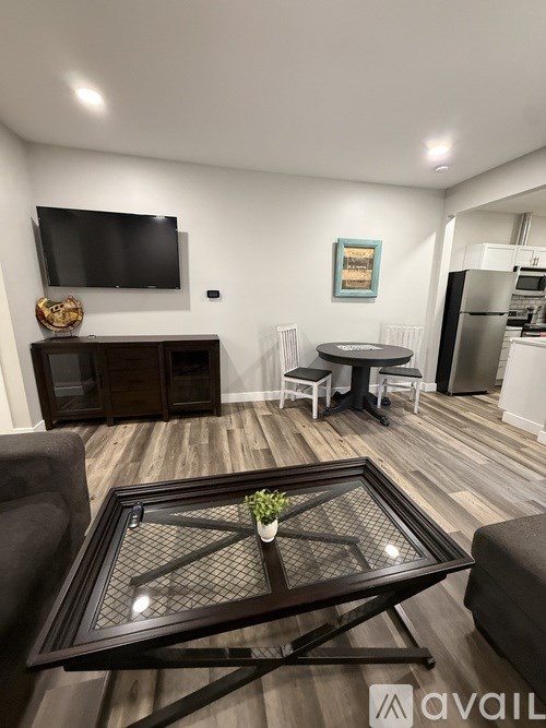 A living room with a black coffee table and a flat screen TV mounted on the wall.