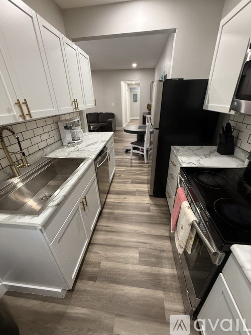 A kitchen with white cabinets and black appliances.