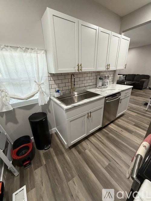 A kitchen with white cabinets and a wooden floor.
