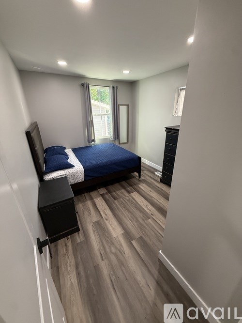 A bedroom with a bed, dresser, and window.