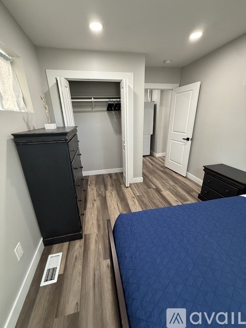 A bedroom with a blue bedspread and a black dresser.
