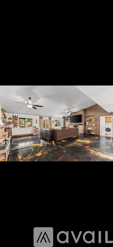 A room with a ceiling fan and a large television set.