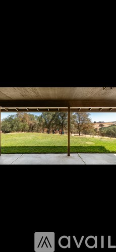 A view from a covered patio looking out to a grassy field.