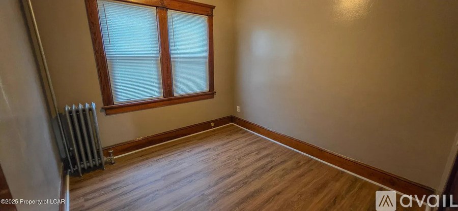 A room with wooden floors and a window with blinds.