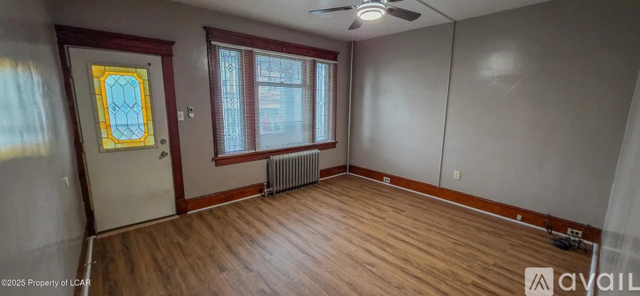 A room with wooden floors and a window with red curtains.