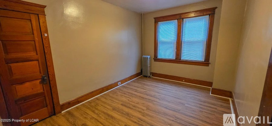 A room with wooden floors and a window with blinds.