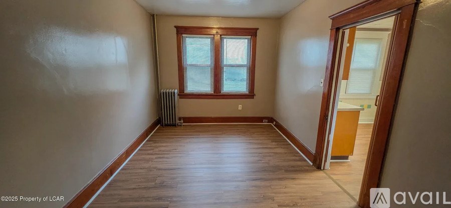 A room with wooden floors and a window with a radiator beneath it.