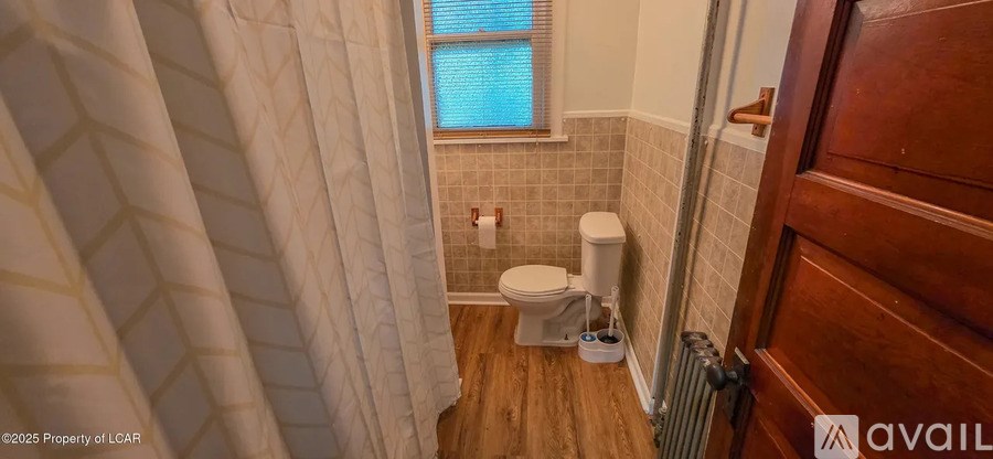 A bathroom with a toilet and a window.