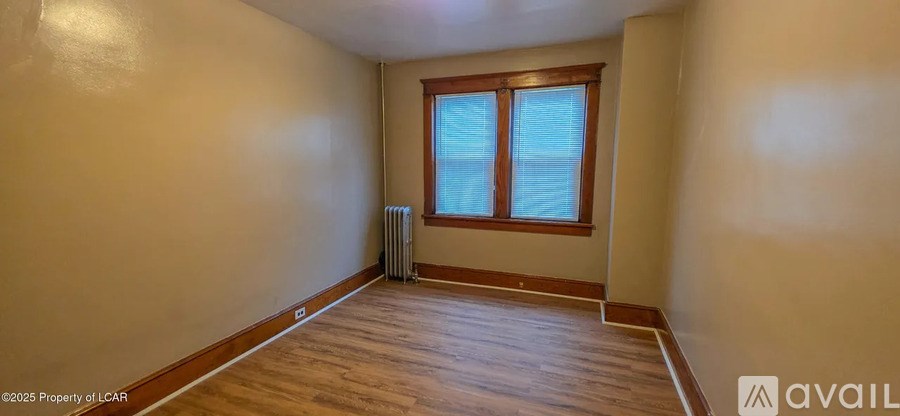 A room with wooden flooring and a window with a white frame.