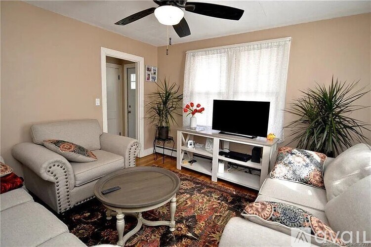 A living room with a grey sofa, a white entertainment center, and a ceiling fan.