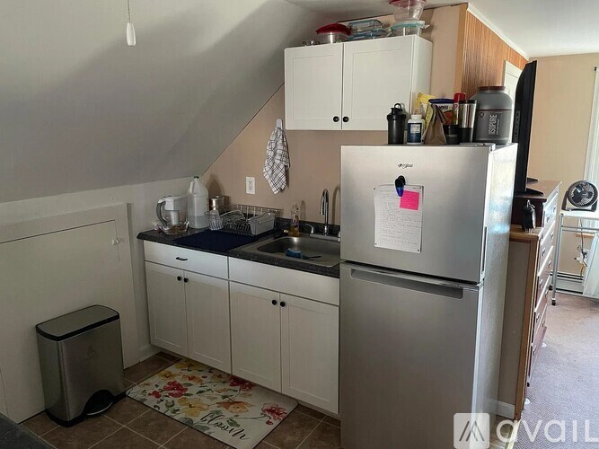 A kitchen with a refrigerator, sink, and cabinets.
