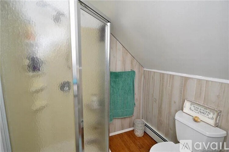 A bathroom with a toilet, a glass, and a towel.