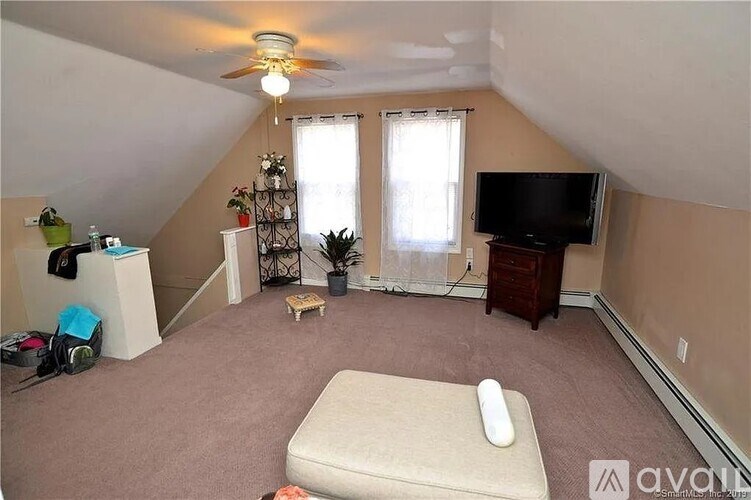 A bedroom with a bed, a television, and a window with curtains.