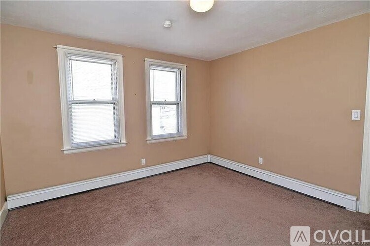 A room with two windows and carpeted floor.