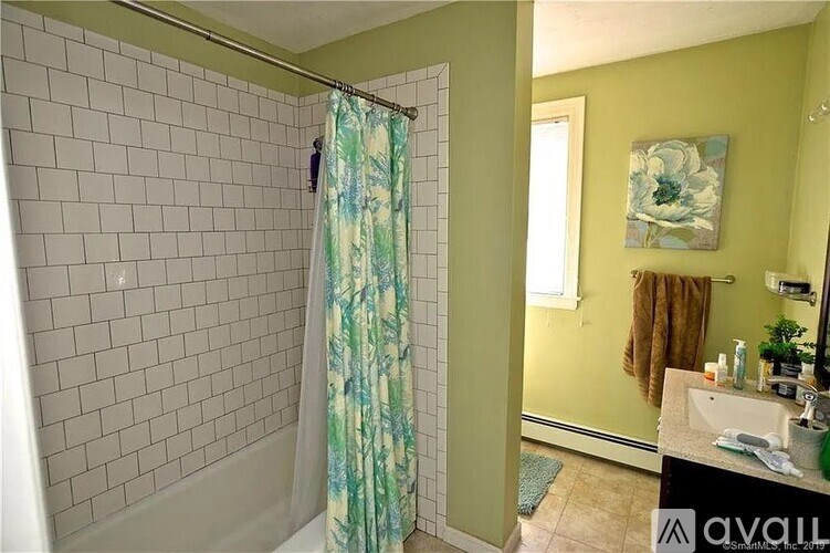 A bathroom with a green shower curtain and a green wall.