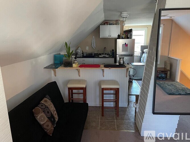 A kitchen with a black couch and wooden stools.