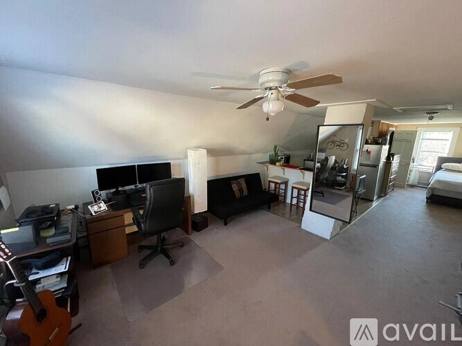 A room with a ceiling fan and a desk with a computer.