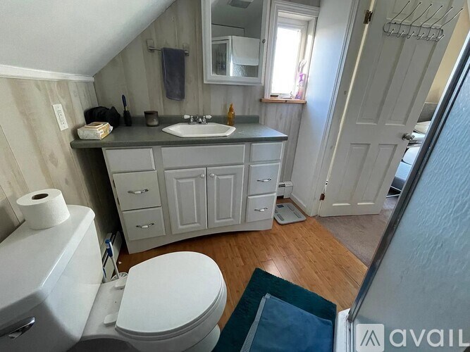 A bathroom with a toilet, sink, and cabinets.