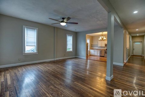 A spacious room with wood flooring and a ceiling fan.
