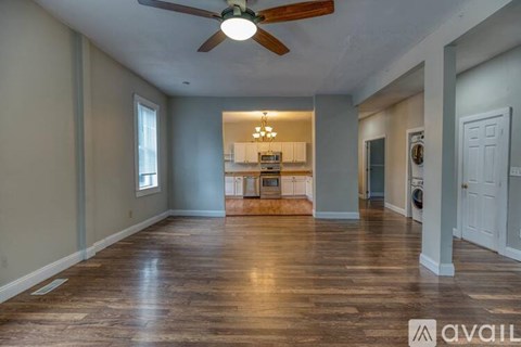 A spacious room with a ceiling fan and hardwood floors.