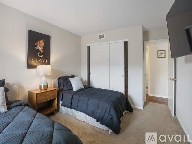 A bedroom with a Gucci poster on the wall and a bed with a blue comforter.