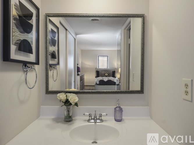 A bathroom with a sink, mirror, and a vase of flowers.