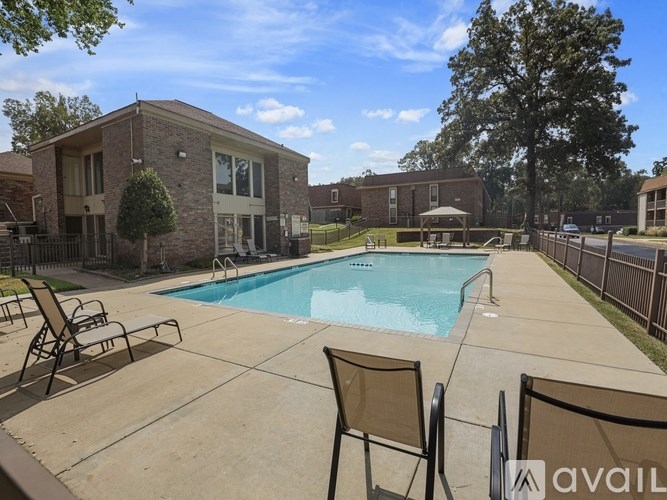 A pool area with chairs and a building in the background.