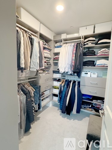 A well-organized walk-in closet with clothes and drawers.