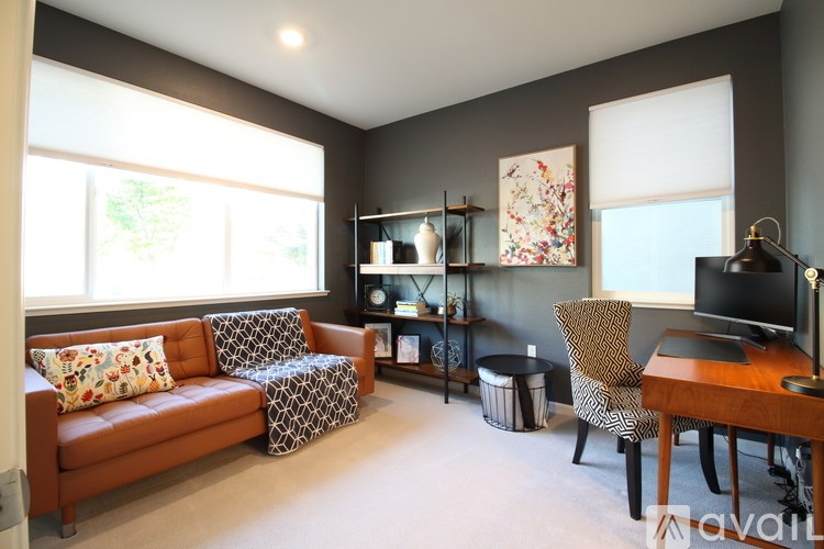 A living room with a brown couch, a chair, a desk, and a television.