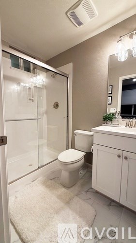 A bathroom with a toilet, sink, and mirror.