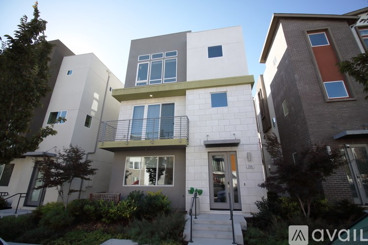 A modern two-story house with a white and grey exterior and a balcony on the second floor.