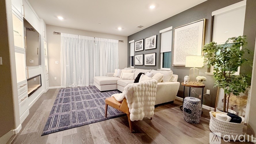 A living room with a couch, a rug, and a potted plant.
