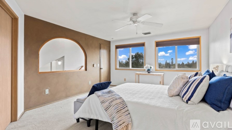 A bedroom with a large bed and a window overlooking a forest.